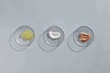 Multicolored texture of cream, scrub, serum, gel in Petri dishes on a gray background. Concept of cosmetics laboratory researches. Smear of skincare cosmetics product. soft focusの写真素材