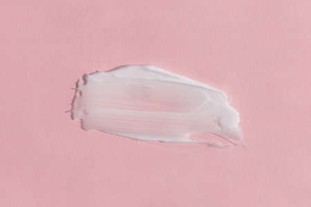 White cream texture on a pink background. Smear of skincare cosmetics product. wellness and beauty concept.の写真素材