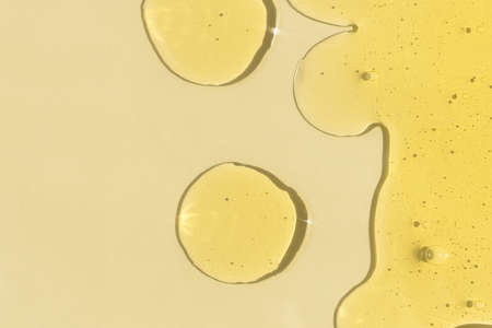 Drops of transparent cosmetic gel or serum yellow on a beige background. The concept of cosmetics or virus protection. top view.の写真素材