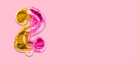 Rainbow foil balloon number, digit two on a pink background. Birthday greeting card with inscription 2. Top view. Numerical digit. Celebration event template. Banner.の写真素材