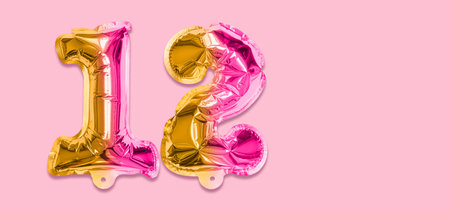 Rainbow foil balloon number, digit twelve on a pink background. Birthday greeting card with inscription 12. Top view. Numerical digit. Celebration event template. Banner.の写真素材