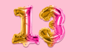 Rainbow foil balloon number, digit thirteen on a pink background. Birthday greeting card with inscription 13. Top view. Numerical digit. Celebration event template. Banner.の写真素材