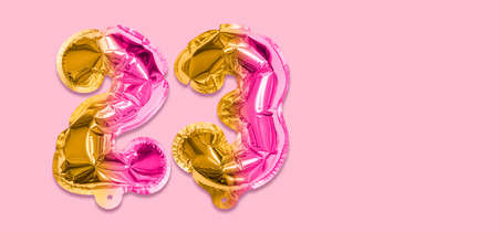 Rainbow foil balloon number, digit twenty three on a pink background. Birthday greeting card with inscription 23. Top view. Numerical digit. Celebration event template. Banner.の写真素材