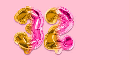 Rainbow foil balloon number, digit thirty two on a pink background. Birthday greeting card with inscription 32. Top view. Numerical digit. Celebration event template. Banner.の写真素材