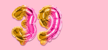 Rainbow foil balloon number, digit thirty nine on a pink background. Birthday greeting card with inscription 39. Top view. Numerical digit. Celebration event template. Banner.の写真素材