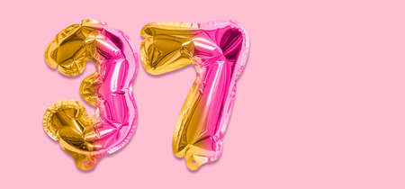 Rainbow foil balloon number, digit thirty seven on a pink background. Birthday greeting card with inscription 37. Top view. Numerical digit. Celebration event template. Banner.の写真素材