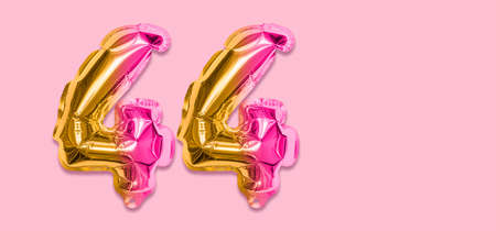 Rainbow foil balloon number, digit forty four on a pink background. Birthday greeting card with inscription 44. Top view. Numerical digit. Celebration event template. Banner.の写真素材