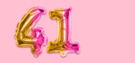 Rainbow foil balloon number, digit forty one on a pink background. Birthday greeting card with inscription 41. Top view. Numerical digit. Celebration event template. Banner.の写真素材