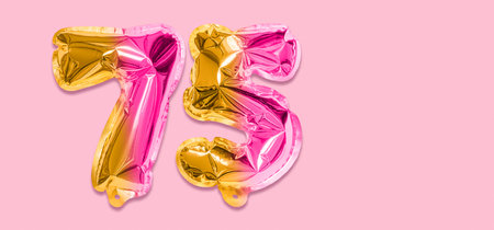 .Rainbow foil balloon number, digit seventy five on a pink background. Birthday greeting card with inscription 75. Anniversary concept. Numerical digit. Celebration event template. Banner.の写真素材