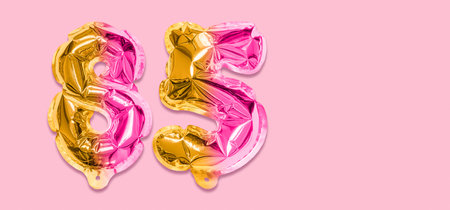 Rainbow foil balloon number, digit eighty five on a pink background. Birthday greeting card with inscription 85. Anniversary concept. Numerical digit. Celebration event template. Banner.の写真素材