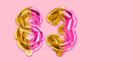 Rainbow foil balloon number, digit eighty three on a pink background. Birthday greeting card with inscription 83. Top view. Numerical digit. Celebration event template. Banner.の写真素材