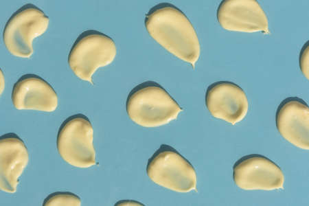 Yellow cream texture on a blue background. Smears of skincare cosmetics product. wellness and beauty concept. top view.の写真素材