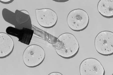 Drops of serum or hyaluronic acid gel with a pipette on a gray background. Smears of cosmetic skin care products. wellness and beauty concept.の写真素材