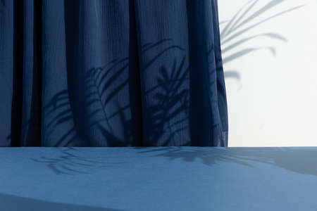 A scene with a blue curtain and the shadow of palm leaves. Premium podium for the presentation of a cosmetic product. empty showcase.の写真素材
