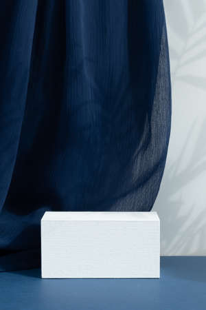 White wooden podium, pedestal on a blue background with curtain and palm shadow. Scene for the presentation of a cosmetic product. empty showcaseの写真素材