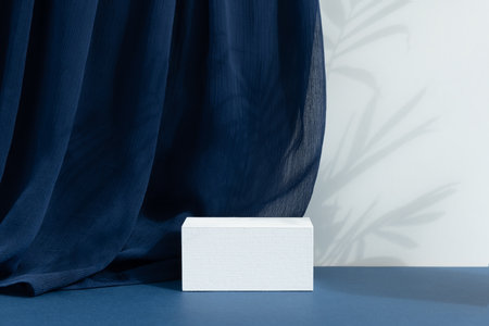 White wooden podium, pedestal on a blue background with curtain and palm shadow. Scene for the presentation of a cosmetic product. empty showcaseの写真素材
