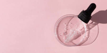 Hyaluronic acid serum or gel for the face with a pipette in Petri dish on a pink background. Concept of cosmetics laboratory researches, wellness and beauty. Bannerの写真素材