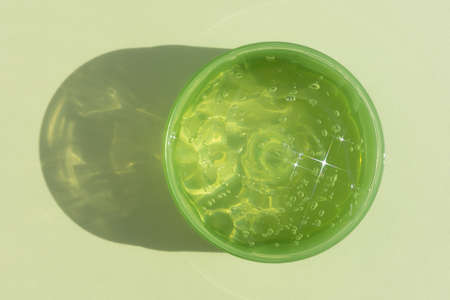 A container with a transparent hyaluronic gel or serum on a green background. cosmetic skincare product. wellness and beauty concept. top view.の写真素材