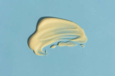 Yellow cream texture on a blue background. A smear of a cosmetic skin care product. wellness and beauty concept. top viewの写真素材