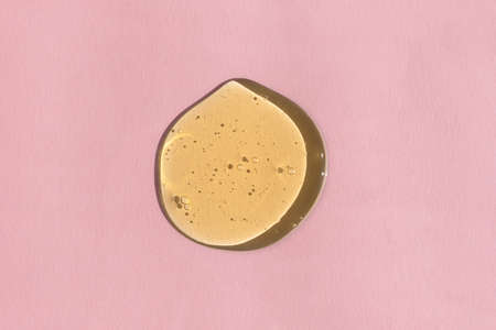 The texture of serum, oil, hyaluronic acid or gel on a pink background. A drop of yellow cosmetic product. wellness and beauty concept.の写真素材
