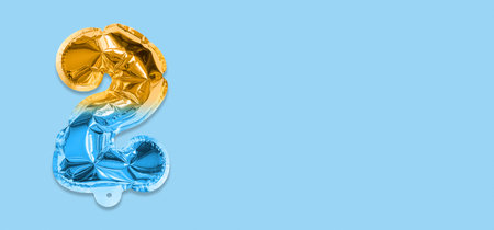 Rainbow foil balloon number, digit two on a blue background. Birthday greeting card with inscription 2. Top view. Numerical digit. Celebration event template. Banner.の写真素材