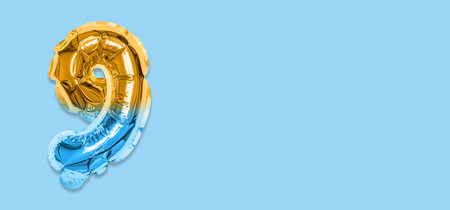 Rainbow foil balloon number, digit nine on a blue background. Birthday greeting card with inscription 9. Top view. Numerical digit. Celebration event template. Banner.の写真素材