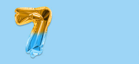 Rainbow foil balloon number, digit seven on a blue background. Birthday greeting card with inscription 7. Top view. Numerical digit. Celebration event template. Banner.の写真素材