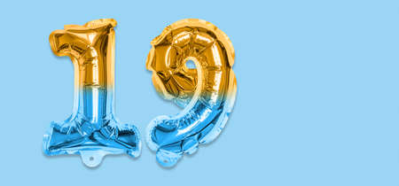 Rainbow foil balloon number, digit nineteen on a blue background. Birthday greeting card with inscription 19. Top view. Numerical digit. Celebration event template. Banner.の写真素材