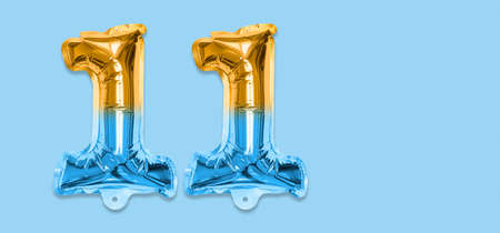 Rainbow foil balloon number, digit eleven on a blue background. Birthday greeting card with inscription 11. Top view. Numerical digit. Celebration event template. Banner.の写真素材