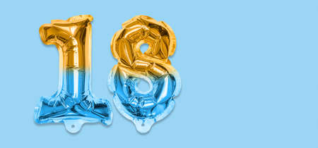 Rainbow foil balloon number, digit eighteen on a blue background. Birthday greeting card with inscription 18. Top view. Numerical digit. Celebration event template. Banner.の写真素材