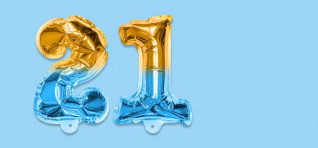 Rainbow foil balloon number, digit twenty one on a blue background. Birthday greeting card with inscription 21. Top view. Numerical digit. Celebration event template. Bannerの写真素材
