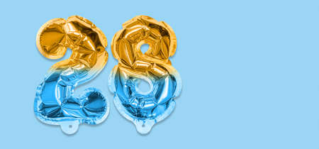 Rainbow foil balloon number, digit twenty eight on a blue background. Birthday greeting card with inscription 28. Top view. Numerical digit. Celebration event template. Bannerの写真素材