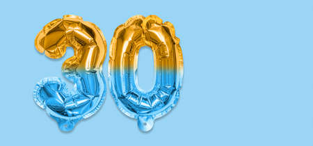Rainbow foil balloon number, digit thirty on a blue background. Birthday greeting card with inscription 30. Anniversary concept. top view. Numerical digit. Celebration event template. Bannerの写真素材