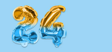 Rainbow foil balloon number, digit twenty four on a blue background. Birthday greeting card with inscription 24. Top view. Numerical digit. Celebration event template. Bannerの写真素材