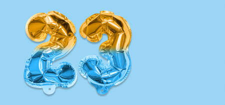 Rainbow foil balloon number, digit twenty three on a blue background. Birthday greeting card with inscription 23. Top view. Numerical digit. Celebration event template. Bannerの写真素材