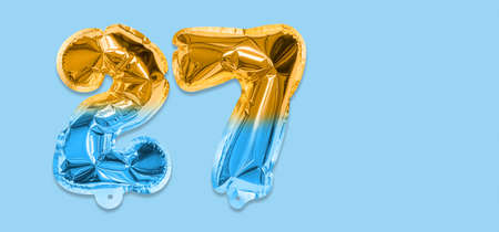 Rainbow foil balloon number, digit twenty seven on a blue background. Birthday greeting card with inscription 27. Top view. Numerical digit. Celebration event template. Bannerの写真素材