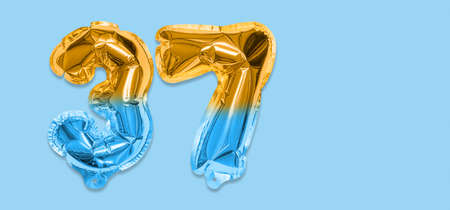 Rainbow foil balloon number, digit thirty seven on a blue background. Birthday greeting card with inscription 37. Top view. Numerical digit. Celebration event template. Bannerの写真素材