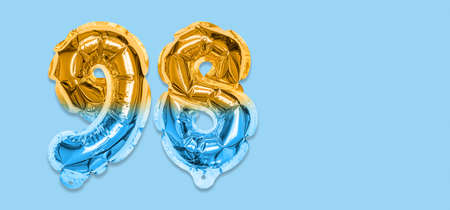 Rainbow foil balloon number, digit ninety eight on a blue background. Birthday greeting card with inscription 98. Top view. Numerical digit. Celebration event template. Bannerの写真素材