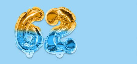 Rainbow foil balloon number, digit sixty two on a blue background. Birthday greeting card with inscription 62. Anniversary concept. top view. Numerical digit. Celebration event template. Bannerの写真素材