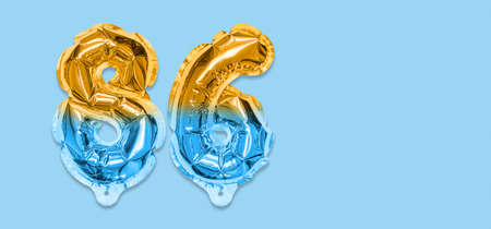 Rainbow foil balloon number, digit eighty six on a blue background. Birthday greeting card with inscription 86. Top view. Numerical digit. Celebration event template. Bannerの写真素材
