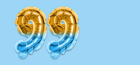 Rainbow foil balloon number, digit ninety nine on a blue background. Birthday greeting card with inscription 99. Top view. Numerical digit. Celebration event template. Bannerの写真素材