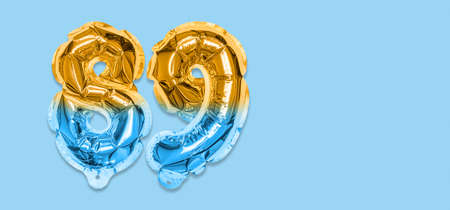 Rainbow foil balloon number, digit eighty nine on a blue background. Birthday greeting card with inscription 89. Top view. Numerical digit. Celebration event template. Bannerの写真素材