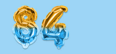 Rainbow foil balloon number, digit eighty four on a blue background. Birthday greeting card with inscription 84. Top view. Numerical digit. Celebration event template. Bannerの写真素材