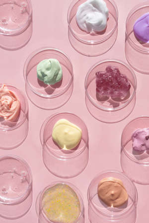 Multicolored textures of cream, scrub, serum and gel in Petri dishes on a pink background. Concept of cosmetics laboratory researches. Smear of skincare cosmetics product. wellness and beauty conceptの写真素材
