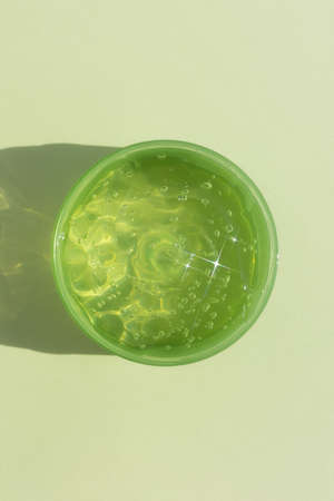 A container with a transparent hyaluronic gel or serum on a green background. cosmetic skincare product. wellness and beauty concept. top view.の写真素材