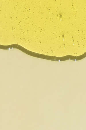 The texture of the antibacterial gel is yellow on a beige background. Serum or hyaluronic acid. The concept of protection against viruses or cosmetics.の写真素材