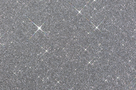 Sparkling texture. Abstract silver background with sparkles in the shape of stars. Festive backdrop for your projects.の写真素材