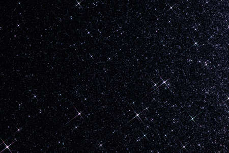 Sparkling texture. Abstract black background with sparkles in the shape of stars. Festive backdrop for your projects. Starry night sky.の写真素材
