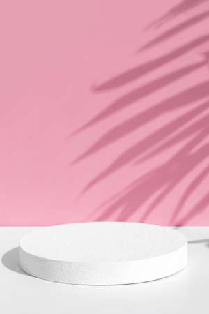 Minimal abstract pink and white background for eco cosmetic product presentation. Cylindrical white scene. Premium podium with a shadow of tropical palm leaves. empty showcase.の写真素材