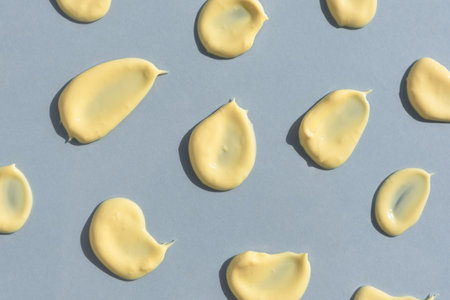 Yellow cream texture on a gray background. Smears of skincare cosmetics product. wellness and beauty concept. top view.の写真素材